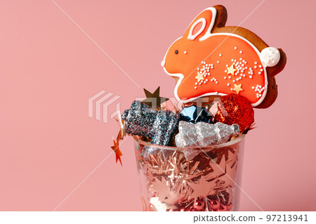 Glass with Christmas decorations on pink pastel background Glass with Christmas decorations on pink pastel background 97213941