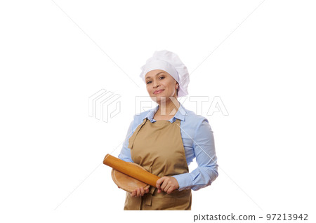 Professional portrait of a confident pretty woman chef-cook, wearing blue casual shirt and beige apron, holding a rolling in and wooden board, smiles looking at camera, isolated on white background Professional portrait of a confident pretty woman chef-cook, wearing blue casual shirt and beige apron, holding a rolling in and wooden board, smiles looking at camera, isolated on white background 97213942