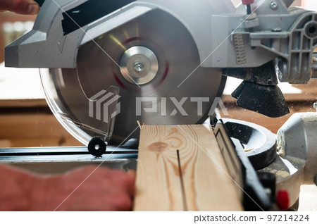 Master cuts the board with a circular saw in the workshop.  97214224
