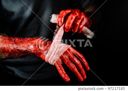 A man covered in blood bandages his hands. A man covered in blood bandages his hands. 97217185