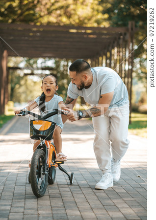Cute little girl looking excited while riding a bike in the park 97219262