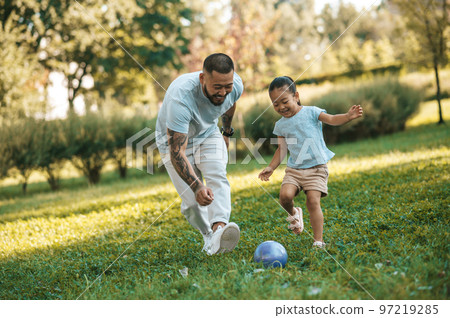 Young man playing football with his daughter in the park 97219285