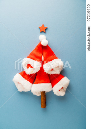 Set of red Santa Claus hats in shape of Christmas tree over blue background, copy space Set of red Santa Claus hats in shape of Christmas tree over blue background, copy space 97219400