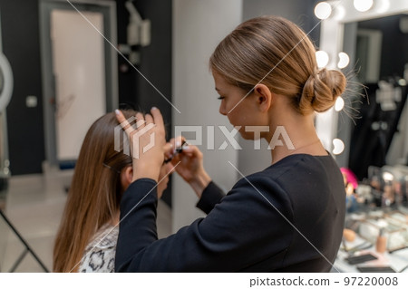 Makeup artist paints eyelashes to a woman in a beauty salon. Makeup artist paints eyelashes to a woman in a beauty salon. 97220008