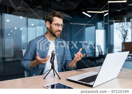 Business coach inside office recording audio podcast, businessman working at laptop using professional microphone and laptop for online radio, and training Remote. Business coach inside office recording audio podcast, businessman working at laptop using professional microphone and laptop for online radio, and training Remote. 97220194