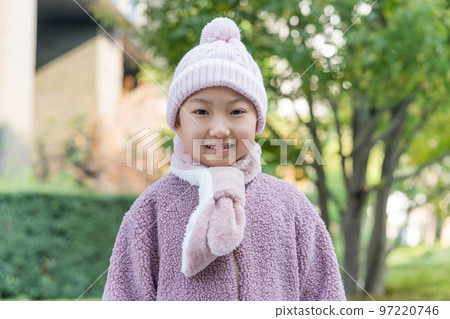 Elementary school girl wearing gloves and a scarf in a knitted hat in winter 97220746