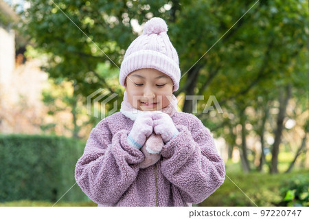 Elementary school girl wearing gloves and a scarf in a knitted hat in winter 97220747