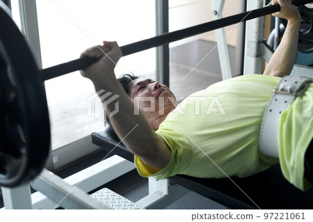 Asian man doing bench press in gym Asian man doing bench press in gym 97221061