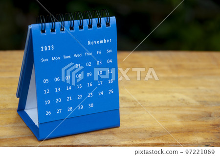 November 2023 blue desk calendar on wooden table background with customizable space for text. Copy space. 97221069
