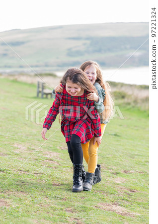 Two little girls sisters playing outdoor near Cuckmere beach located between Eastbourne and Seaford, East Sussex, British south coast, selective focus 97221324
