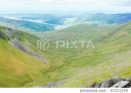 Climbing up mountain range in North Wales, United Kingdom. Rural landsapes, green grass, cloudy sky, selective focus 97221339