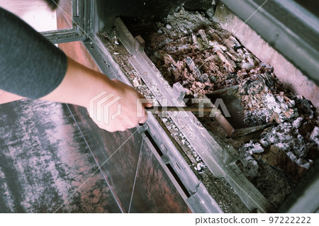 Fireplace cleaning. Woman hand holds a shovel with ash.A hand collects ash from the fireplace on an old steel blade. Daily winter routine Fireplace cleaning. Woman hand holds a shovel with ash.A hand collects ash from the fireplace on an old steel blade. Daily winter routine 97222222