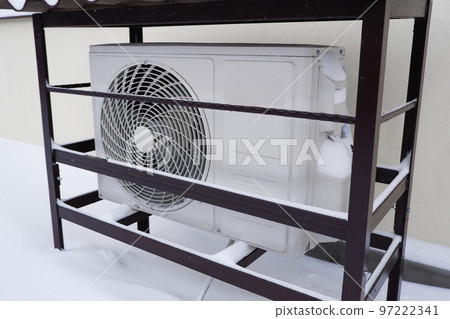 The outdoor unit of the air conditioner (air-to-air heat pump) in the snow during winter operation. The outdoor unit of the air conditioner (air-to-air heat pump) in the snow during winter operation. 97222341