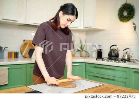 Young beautiful brunette woman in her 30s cooks in the kitchen 97222473