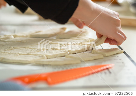 A close-up view of the hands of a housewife in the process of cooking baursaks in the kitchen 97222506