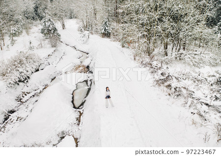 A stylish woman with a white suit with a New Year's gift in her hands in a winter forest. A girl in nature in a snowy forest with a gift box A stylish woman with a white suit with a New Year's gift in her hands in a winter forest. A girl in nature in a snowy forest with a gift box 97223467