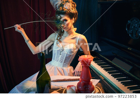 Duchess. Portrait of young beautiful girl in image of medieval person in elegant white dress sitting at the piano. Comparison of eras, beauty, history, art 97223853