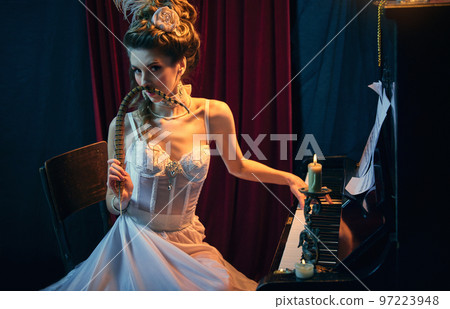 Magic. Portrait of mysterious young lady, medieval person in elegant white dress sitting at the piano and performing. Comparison of eras, beauty, history, art Magic. Portrait of mysterious young lady, medieval person in elegant white dress sitting at the piano and performing. Comparison of eras, beauty, history, art 97223948