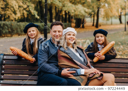 A large family is sitting on a bench in an autumn park. Happy people in the autumn park A large family is sitting on a bench in an autumn park. Happy people in the autumn park 97224449