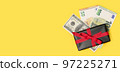 black gift box with a cash money on a yellow background. Holiday background 97225271