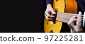 Guitarist playing acoustic guitar on black background, selective focus. 97225281