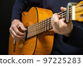 Guitarist playing acoustic guitar on black background, selective focus. 97225283