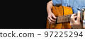 Guitarist playing acoustic guitar on black background, selective focus. 97225294