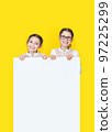 Girls sisters holding white empy poster and smiling. 97225299