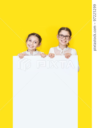 Girls sisters holding white empy poster and smiling. Girls sisters holding white empy poster and smiling. 97225299