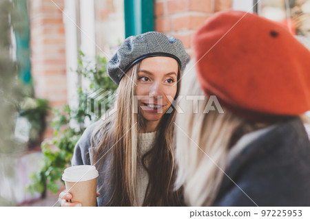 Young female best friends talking to each other discussing interesting themes during free time hipster girls joking and having fun together enjoying recreation with coffee to go on urban background Young female best friends talking to each other discussing interesting themes during free time hipster girls joking and having fun together enjoying recreation with coffee to go on urban background 97225953