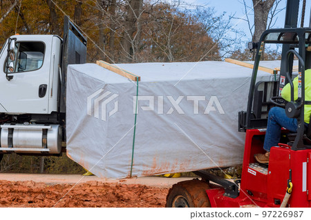 Man using forklift working on unloading construction parts of building materials Man using forklift working on unloading construction parts of building materials 97226987