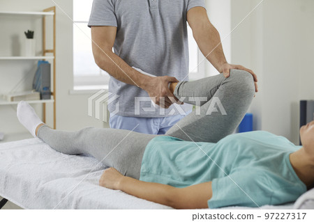Professional chiropractor, osteopath or physiotherapist examining young woman's knee Professional chiropractor, osteopath or physiotherapist examining young woman's knee 97227317