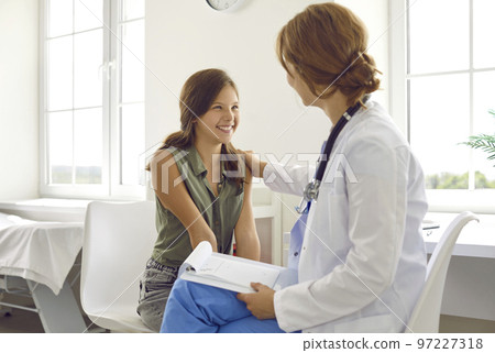 Friendly pediatrician talking to happy teenage girl, supporting and reassuring her Friendly pediatrician talking to happy teenage girl, supporting and reassuring her 97227318