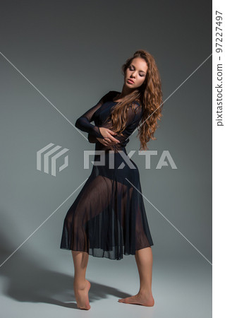Beautiful woman dancer wearing black dress posing on a grey studio background 97227497