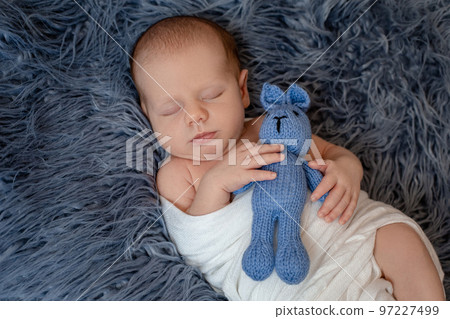 Newborn baby boy in bed. New born child sleeping under a white knitted blanket. Children sleep. 97227499