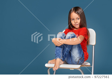 little girl wearing red t-short and posing on chair 97227561