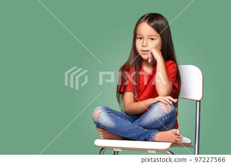little girl wearing red t-short and posing on chair 97227566