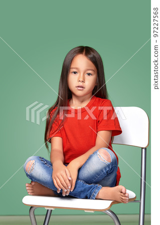 little girl wearing red t-short and posing on chair 97227568