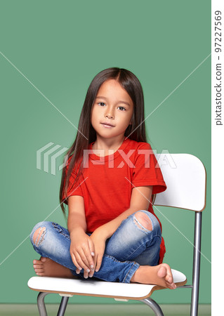 little girl wearing red t-short and posing on chair little girl wearing red t-short and posing on chair 97227569