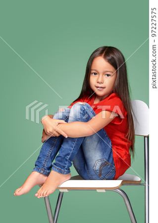 little girl wearing red t-short and posing on chair little girl wearing red t-short and posing on chair 97227575
