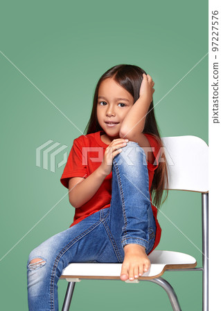 little girl wearing red t-short and posing on chair 97227576