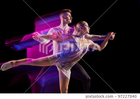 Portrait of young man and woman, figure skating athletes dancing isolated over black background in neon with mixed lights 97227840