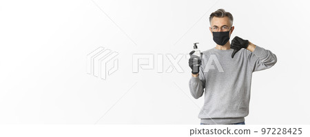 Concept of coronavirus, lifestyle and quarantine. Portrait of middle-aged man in medical mask and gloves do not recommend antiseptic, showing hand sanitizer and thumbs-down, white background Concept of coronavirus, lifestyle and quarantine. Portrait of middle-aged man in medical mask and gloves do not recommend antiseptic, showing hand sanitizer and thumbs-down, white background 97228425