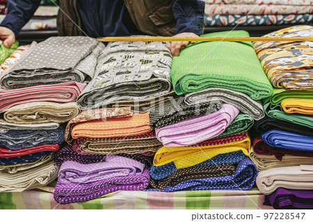Colorful fabric rolls on counter of textile shop. Hands of salesman working at textile shop 97228547