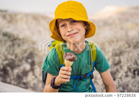 Boy tourist boy eating turkish ice cream while exploring valley with rock formations and fairy caves near Goreme in Cappadocia Turkey 97228638