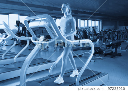 Young woman walking on treadmill in gym 97228910