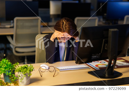Business woman staying in the company and working late Business woman staying in the company and working late 97229099