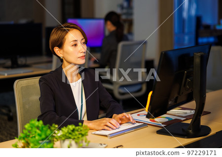 Business woman staying in the company and working late Business woman staying in the company and working late 97229171