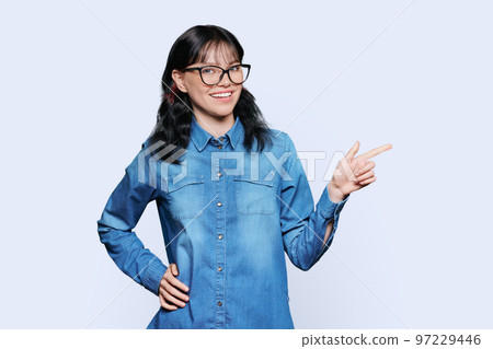 Teenager girl student pointing with hand at empty space for text, white background Teenager girl student pointing with hand at empty space for text, white background 97229446