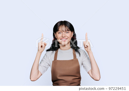 Young woman in apron showing hands up, to empty space for your advertisement 97229451